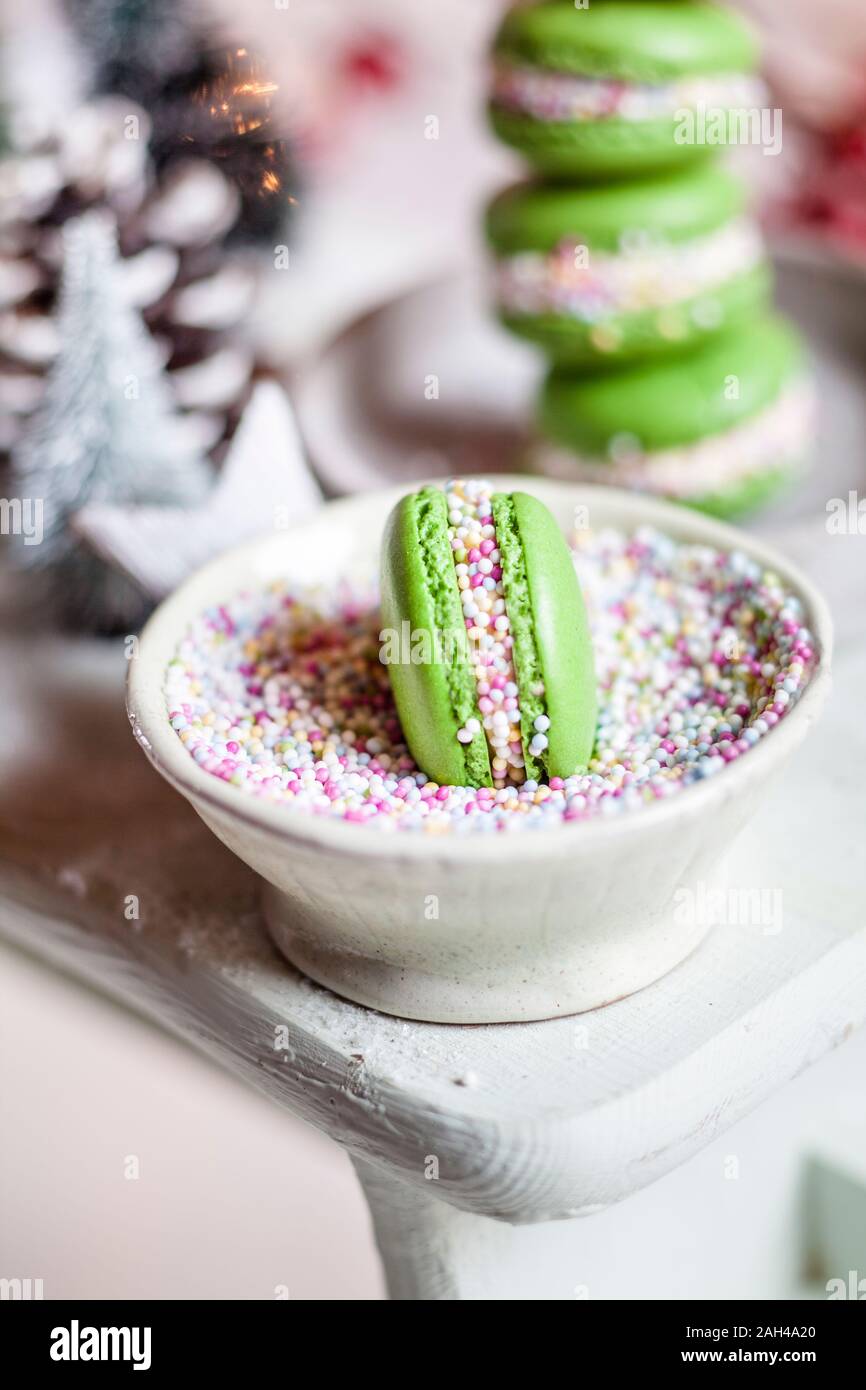 Green macaroon in bowl of colorful sprinklings Stock Photo
