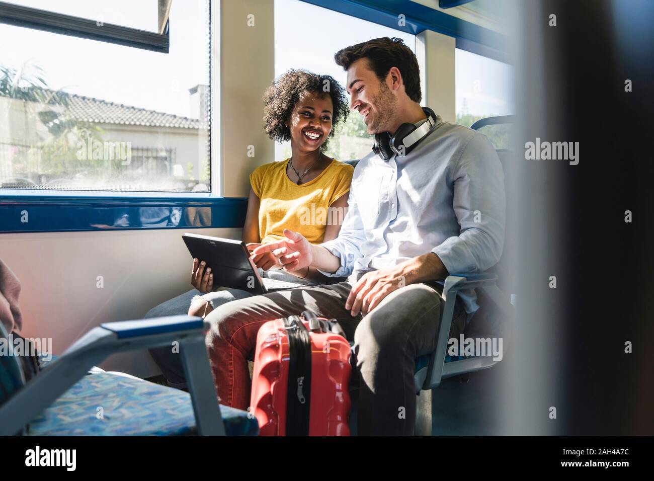 Happy young couple using tablet in a train Stock Photo