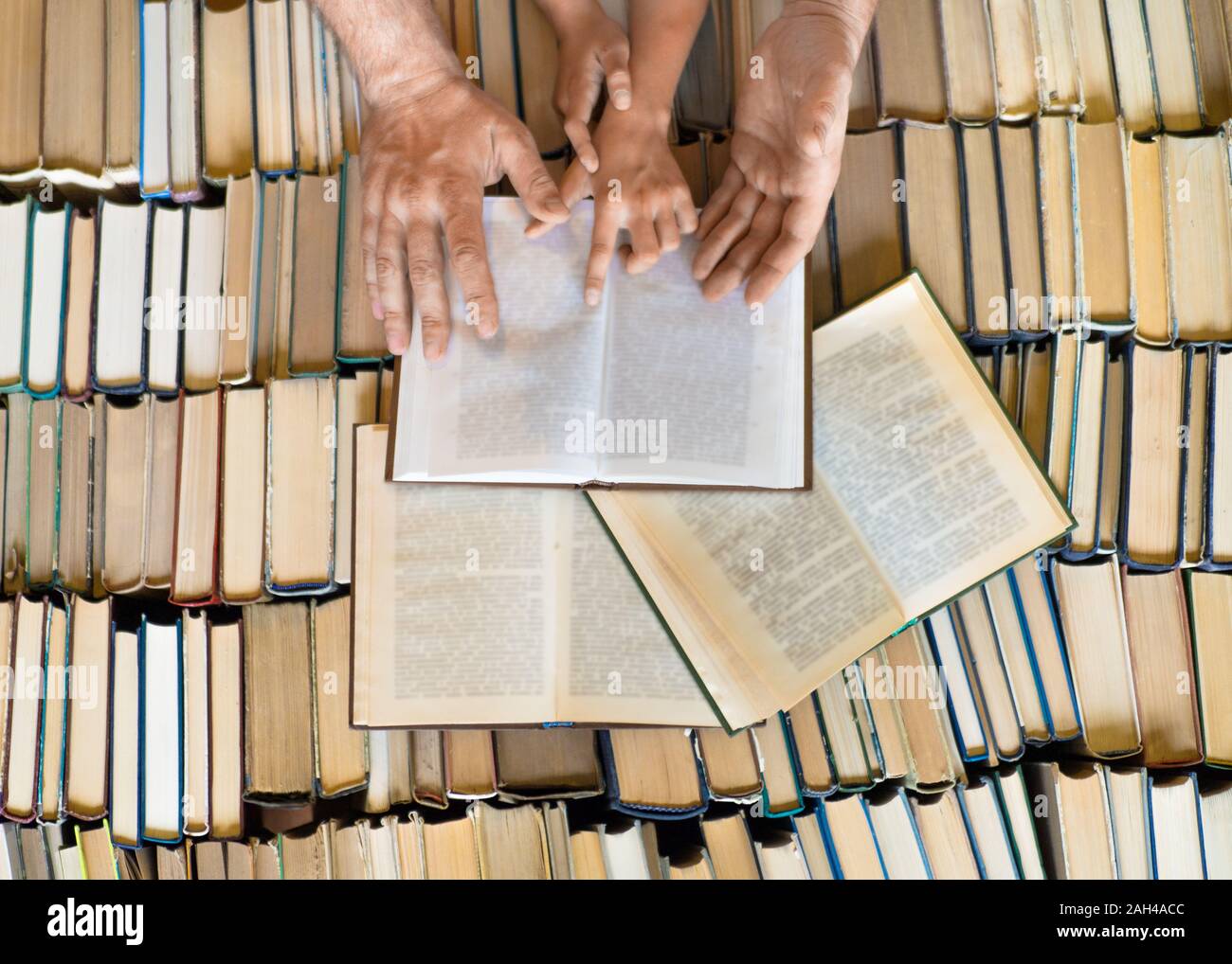 Hands of a man and kid over a lot of books. Teaching, study and knouledge concept. Father teachig his daughter Stock Photo