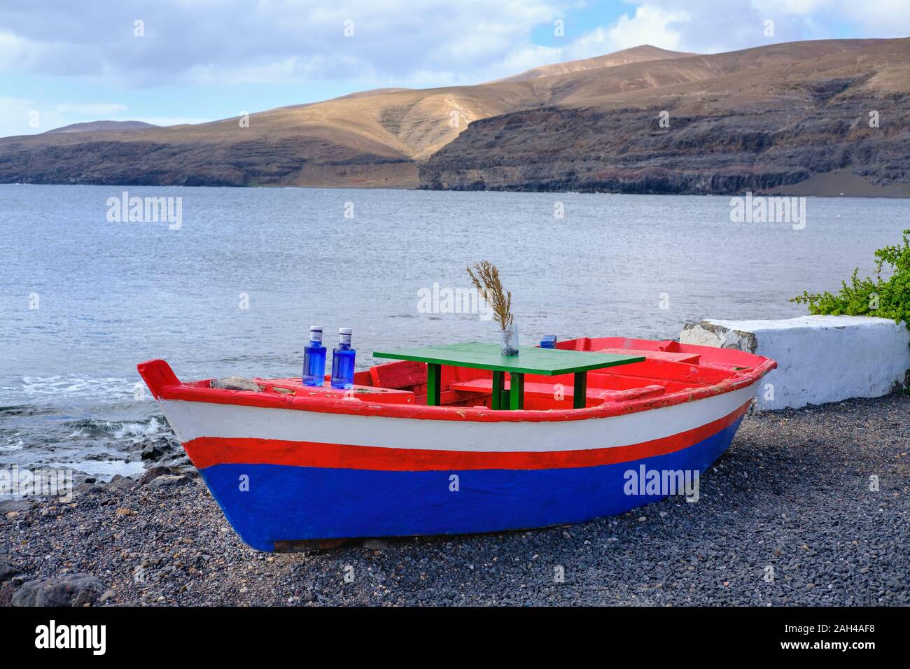 Spain, Canary Islands, Lanzarote,Yaiza, Playa Quemada, Colorful boat with table and bottles Stock Photo