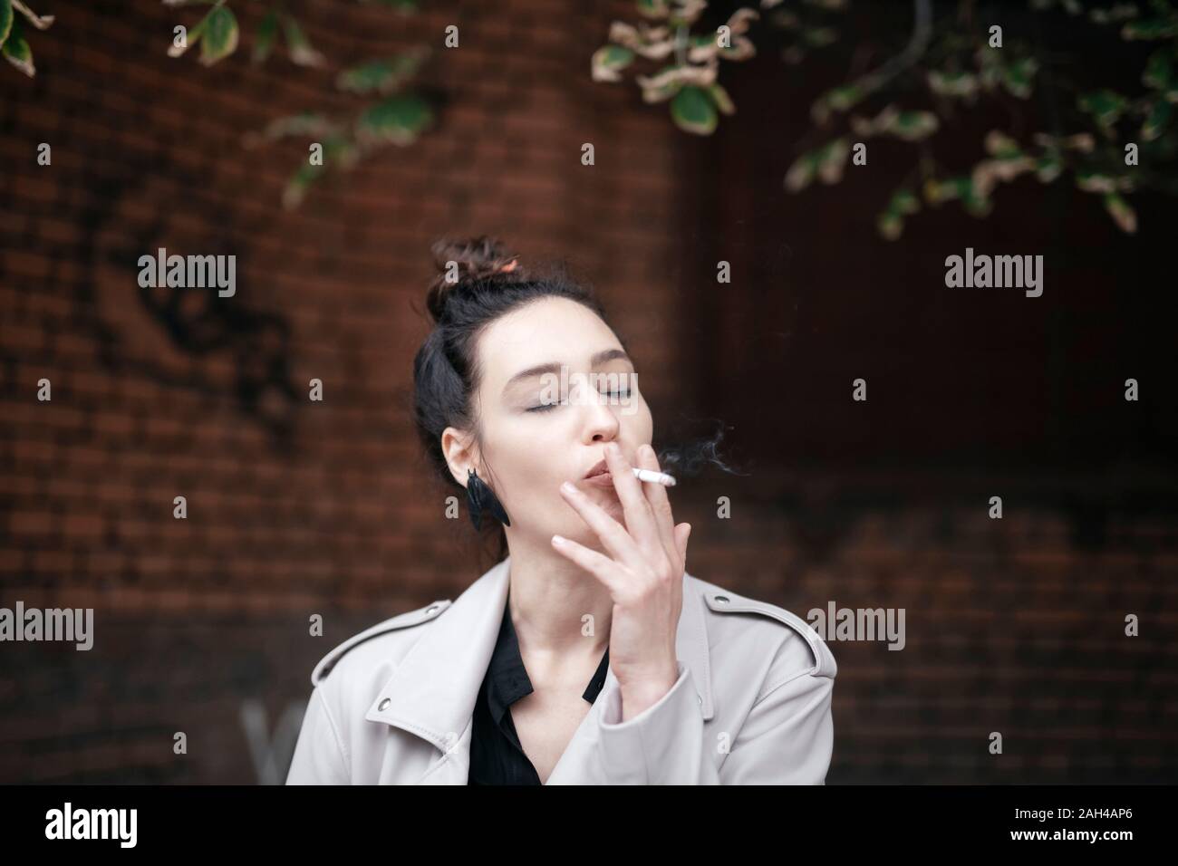 Portrait of woman smoking with eyes closed Stock Photo