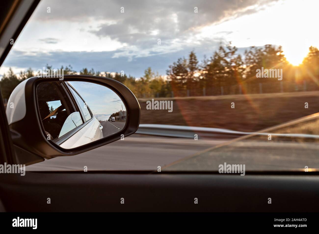 Voronezh, Voronezh Oblast, Russia, Shiny side-view mirror with sun setting in background Stock Photo