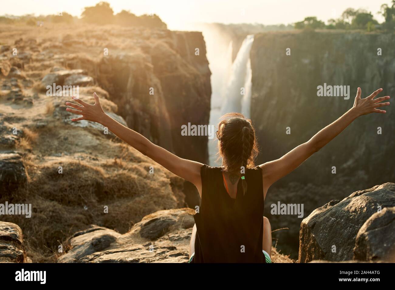 Woman with arms open enjoying the view to Victoria Falls, Zimbabwe Stock Photo