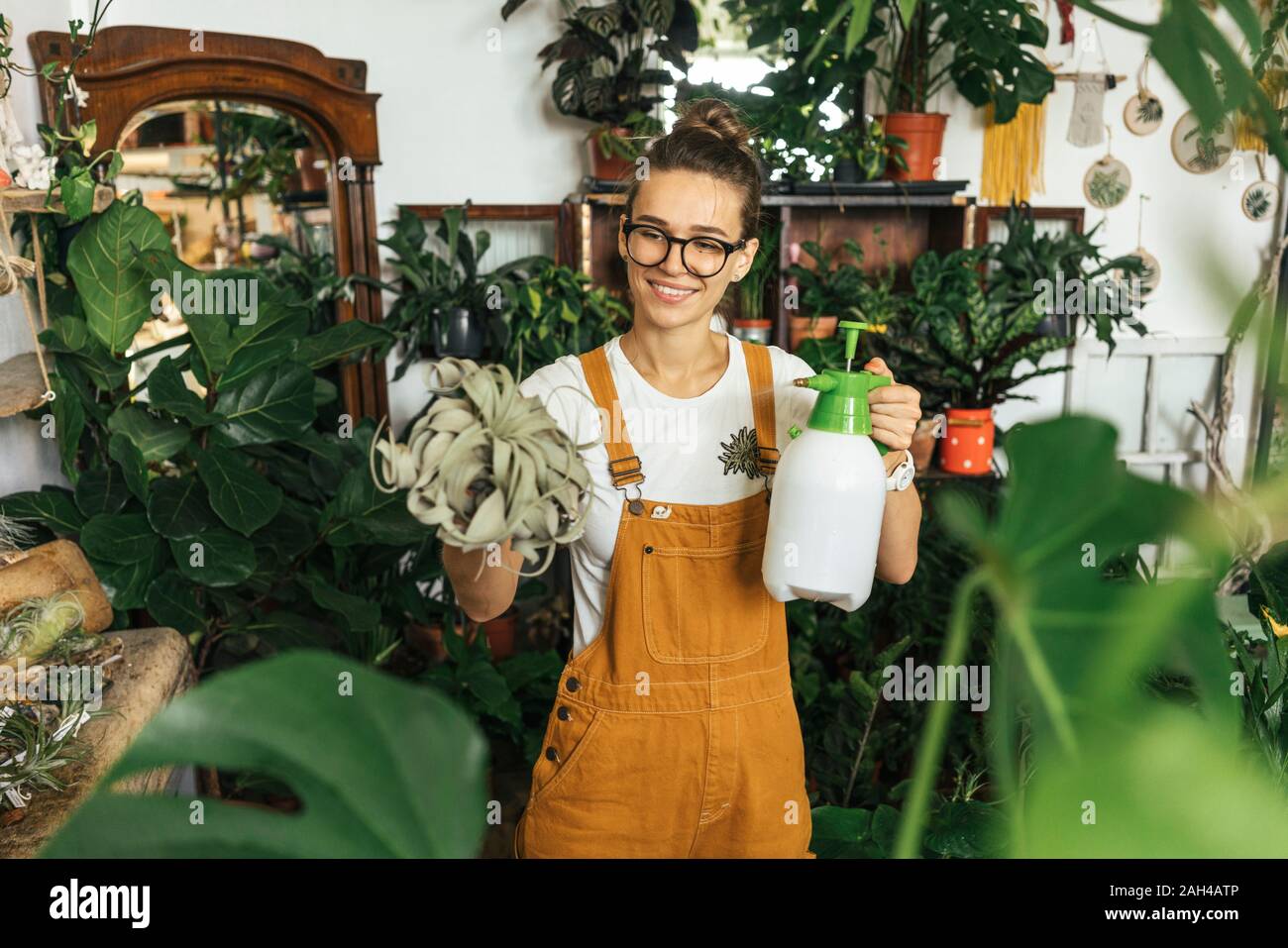 Smiling young woman caring for plants in a small shop Stock Photo