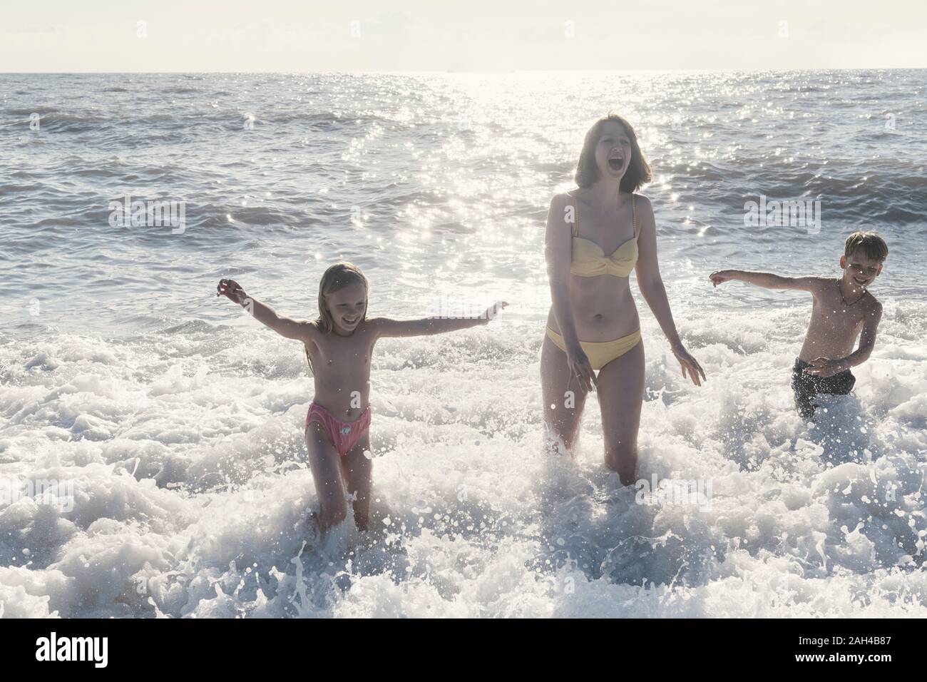 Happy mother with two kids having fun in the sea Stock Photo