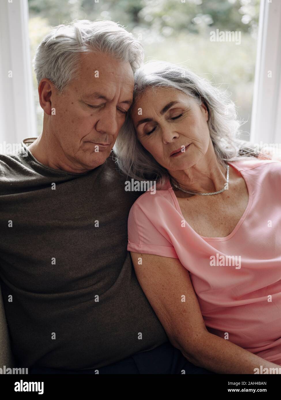 Senior couple napping on couch at home Stock Photo