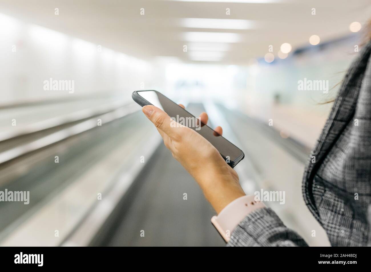 Young businesswoman using smartphone on moving walkway Stock Photo