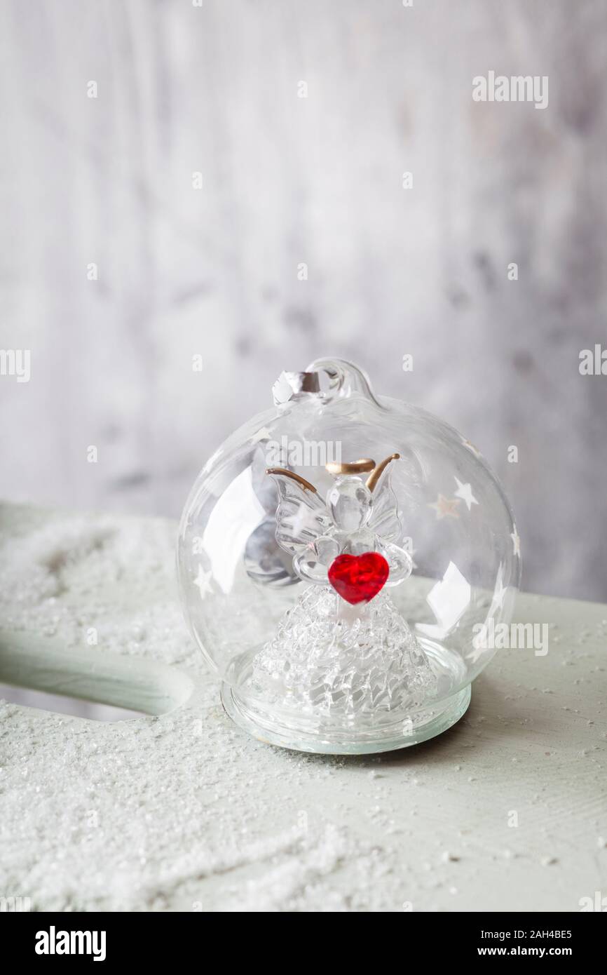 Close up of glass Christmas bauble with angel figurine inside and red heart Stock Photo