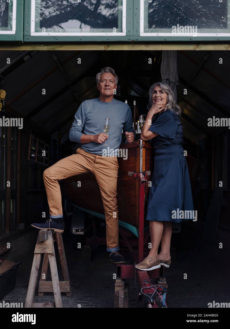 Senior couple in a boathouse with glass of champagne Stock Photo