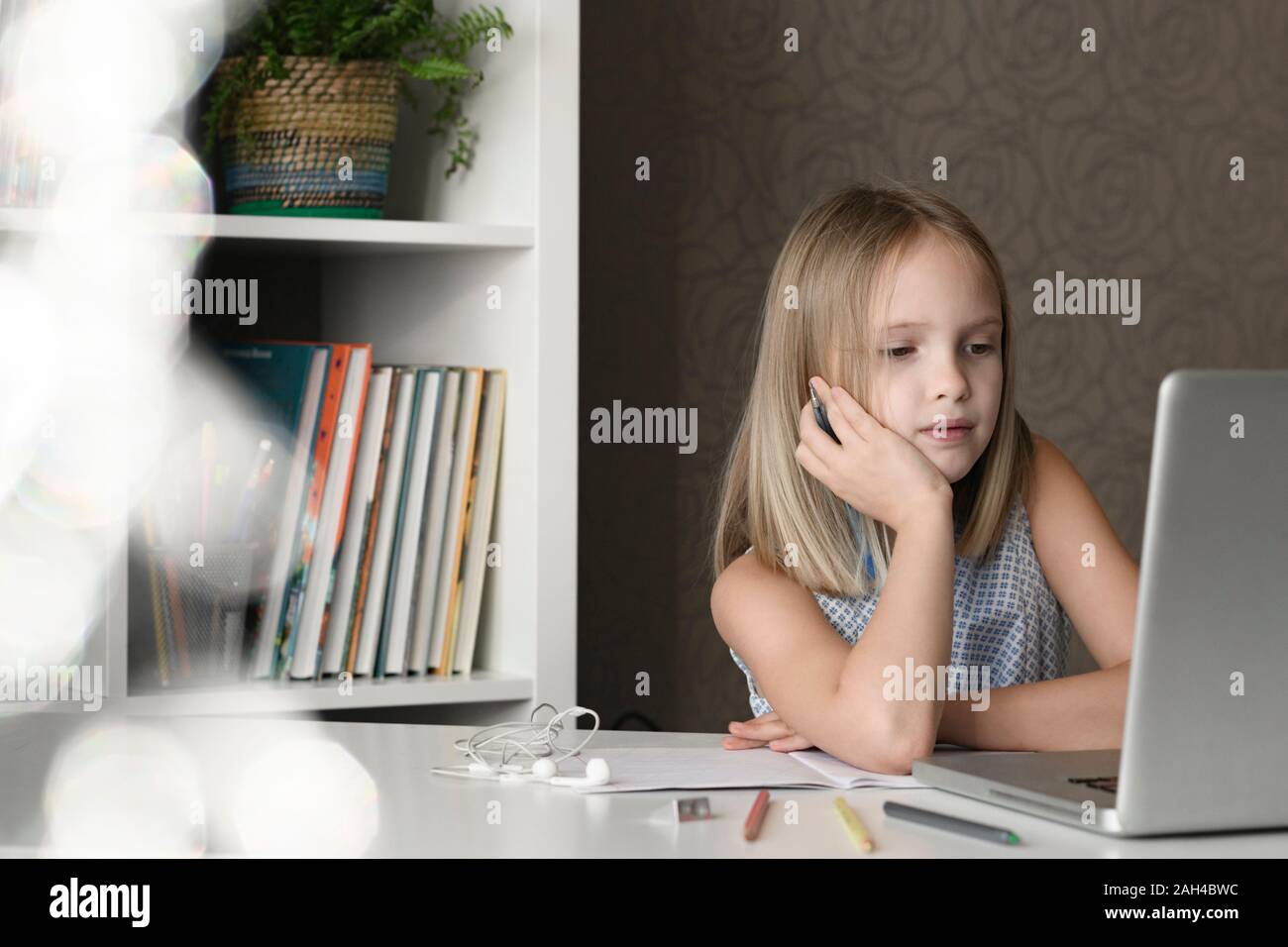 Girl sitting at table at home using laptop Stock Photo