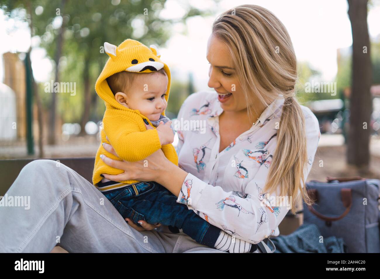 Happy mother resting with baby boy on a park bench Stock Photo - Alamy