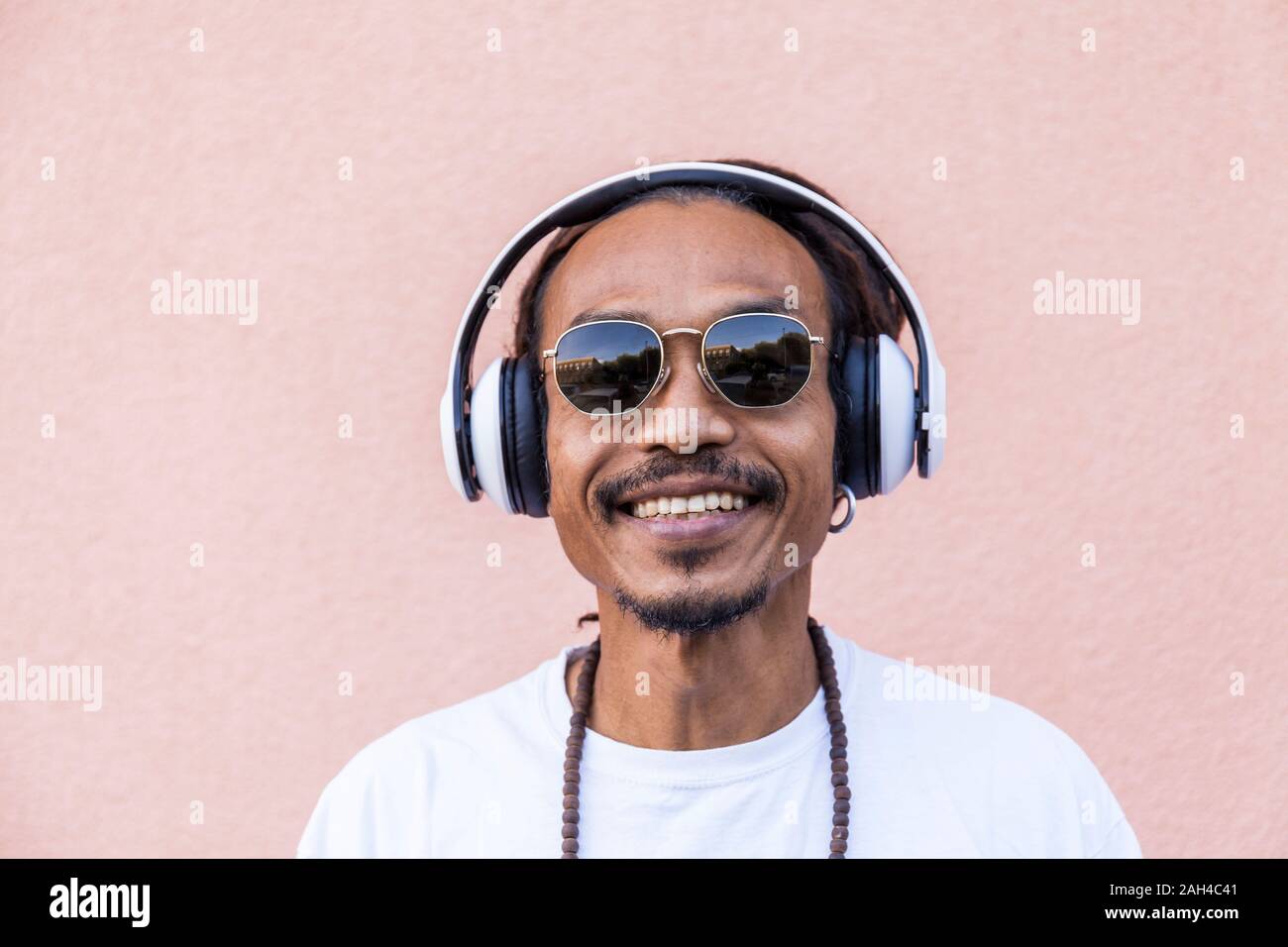 Portrait of mature man with dreadlocks and headphones, listening music Stock Photo