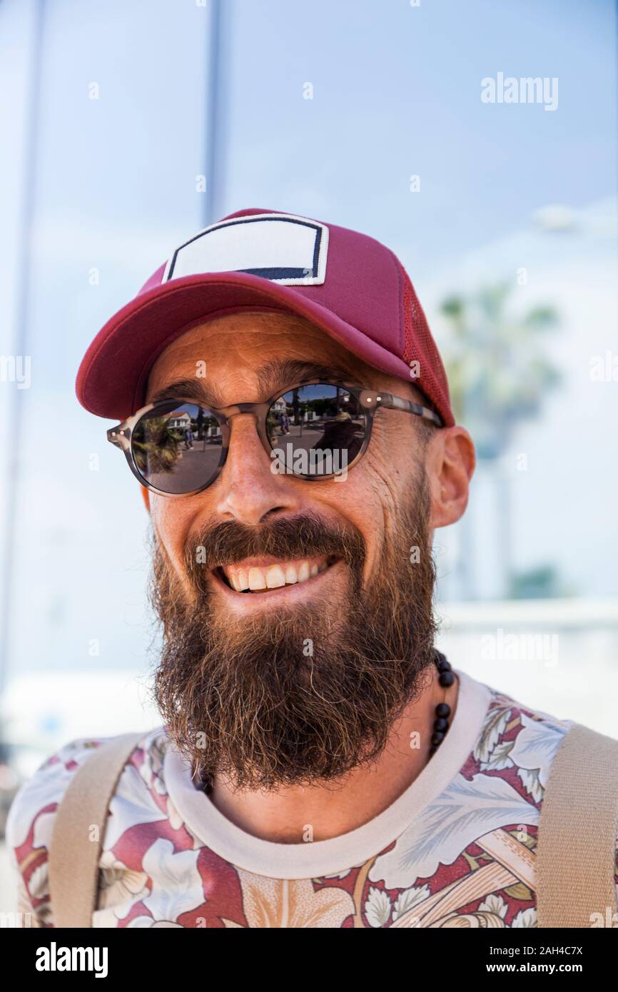 Smiling mature man with beard, red basecap and sunglasses Stock Photo