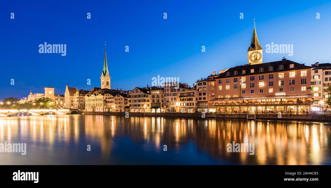 Switzerland, Canton of Zurich, Zurich, River Limmat and old town buildings along illuminated Limmatquai street at dusk Stock Photo