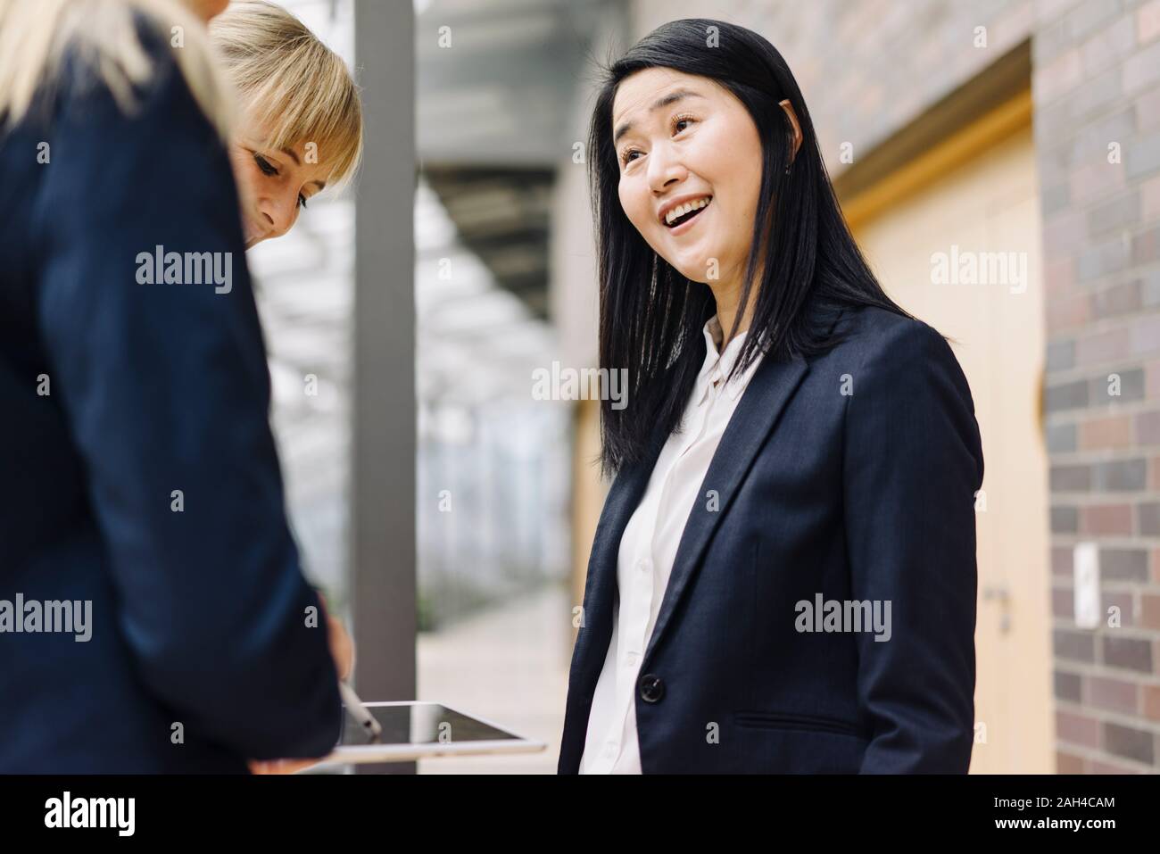 Portrait of happy businesswoman with colleagues in modern office building Stock Photo