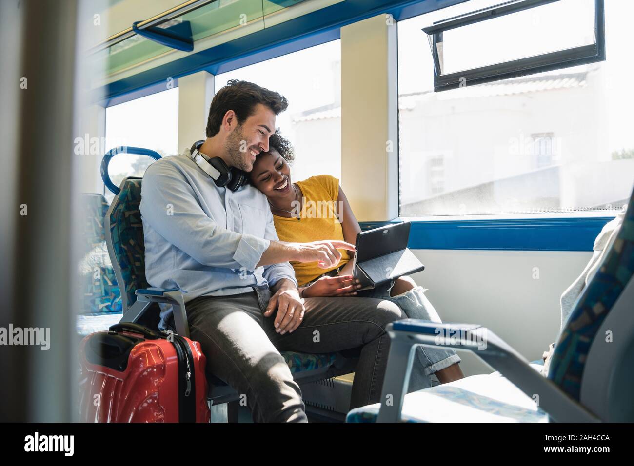Happy young couple using tablet in a train Stock Photo