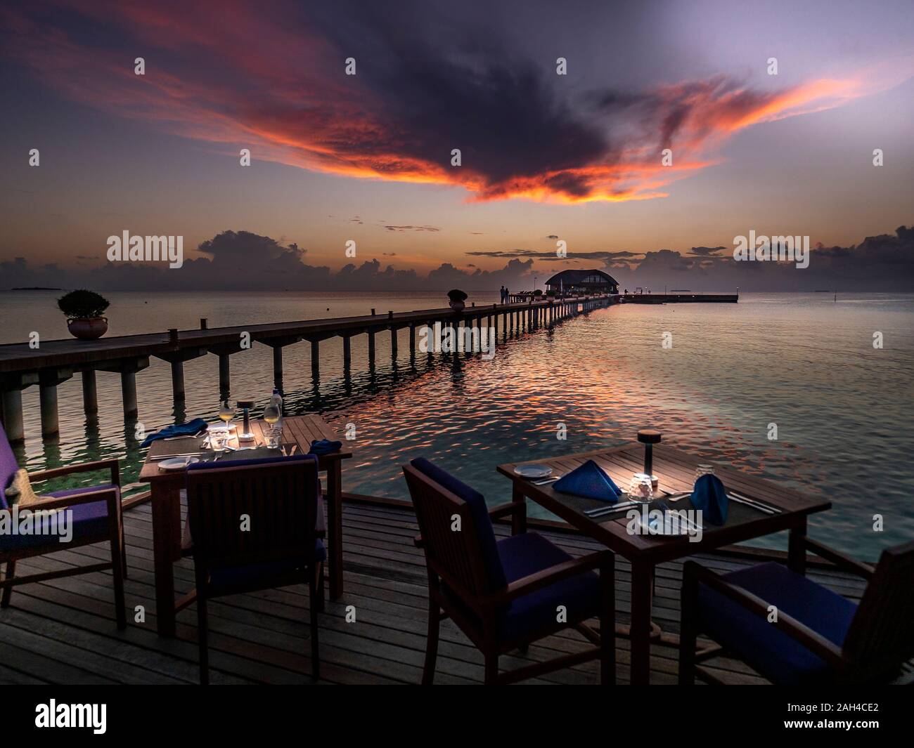 Maldives, Dining tables of coastal restaurant at dusk with pier in background Stock Photo