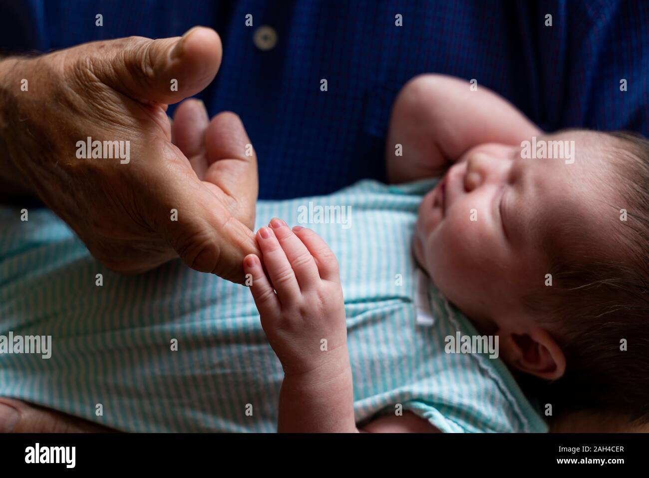 Sleeping newborn baby holding grandfathers finger Stock Photo