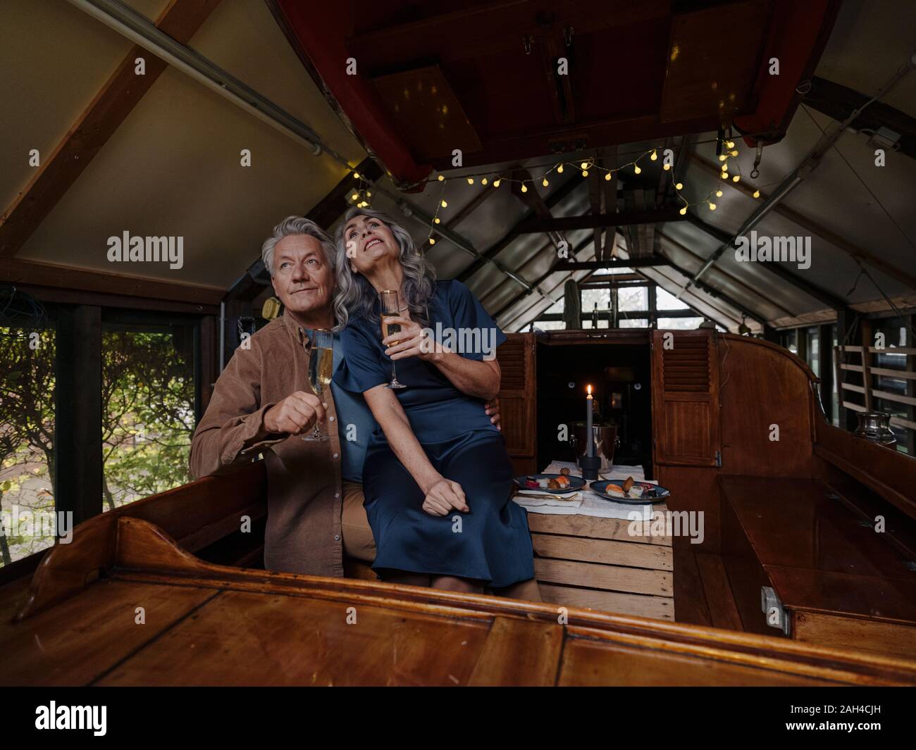 Senior couple having a candlelight dinner on a boat in boathouse Stock Photo