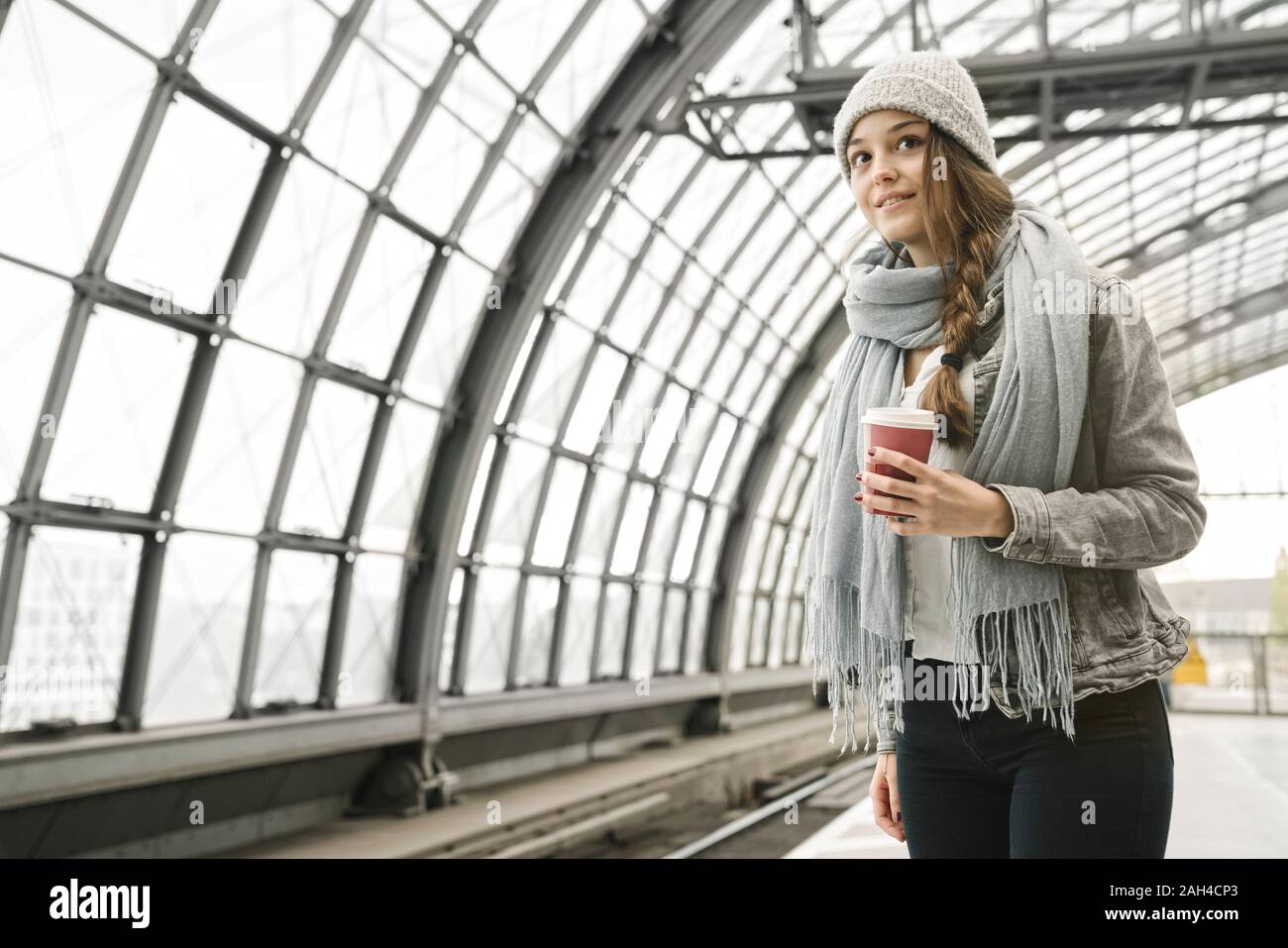 Young woman with takeaway coffee waiting at the station platform, Berlin, Germany Stock Photo