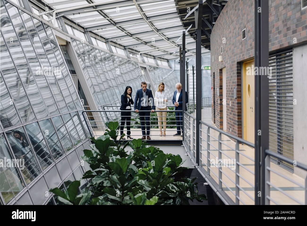Business people standing on skywalk in modern office building Stock Photo
