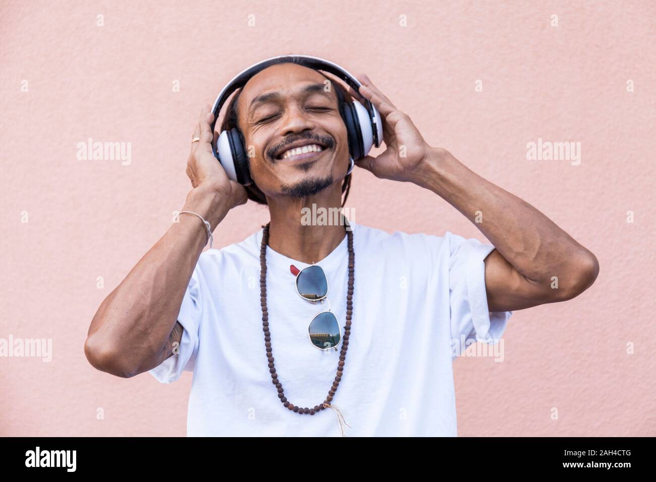 Portrait of mature man with dreadlocks and headphones, listening music with closed eyes Stock Photo