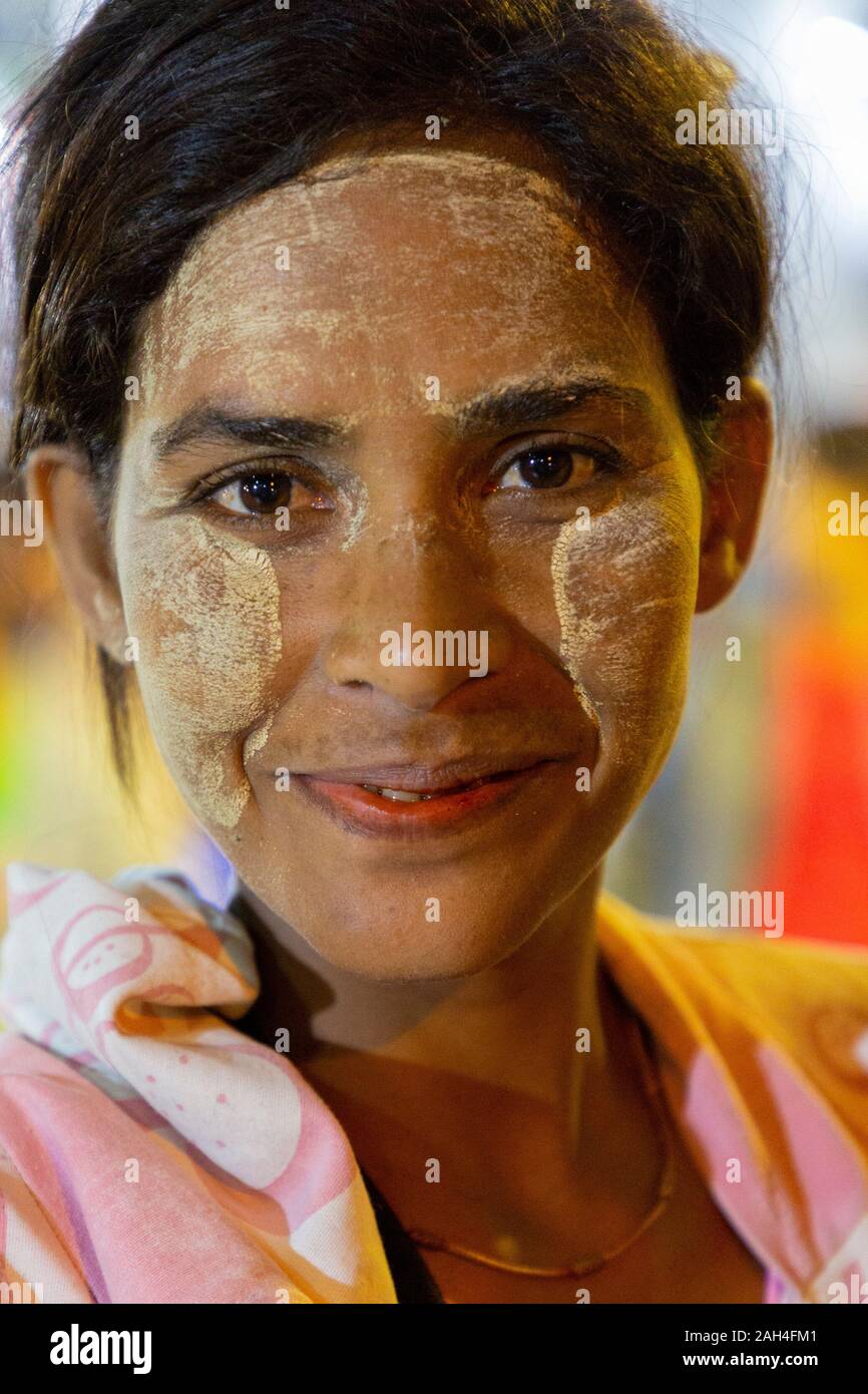 Portrait of local woman with thanaka on her face, in Yangon, Myanmar. Thanaka is cosmetic paste made from ground bark Stock Photo