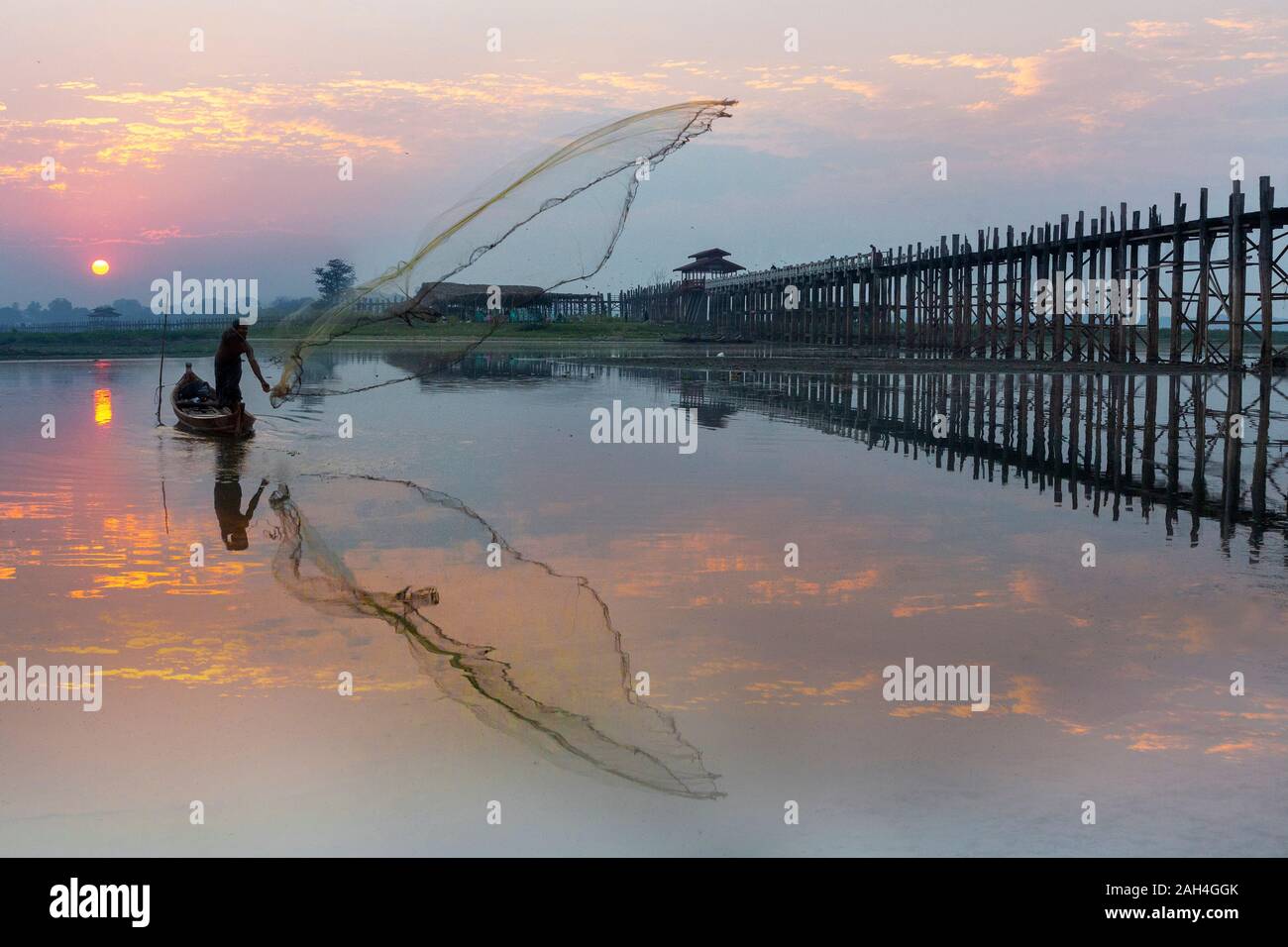 Fisherman setting his net at the sunrise near the U Bein bridge, in Mandalay, Myanmar Stock Photo