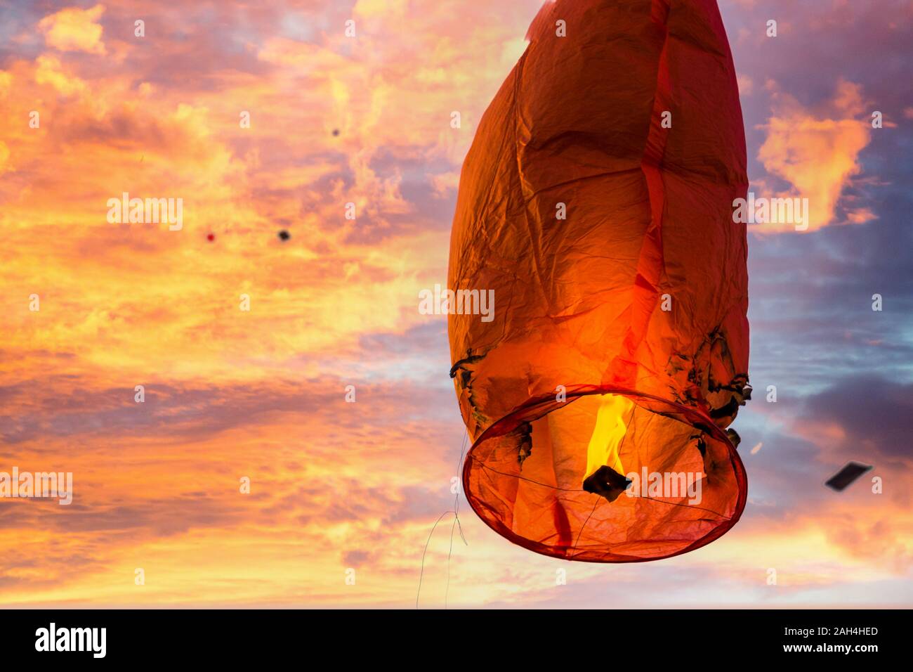 Burnt damaged sky lantern with kites in background Stock Photo
