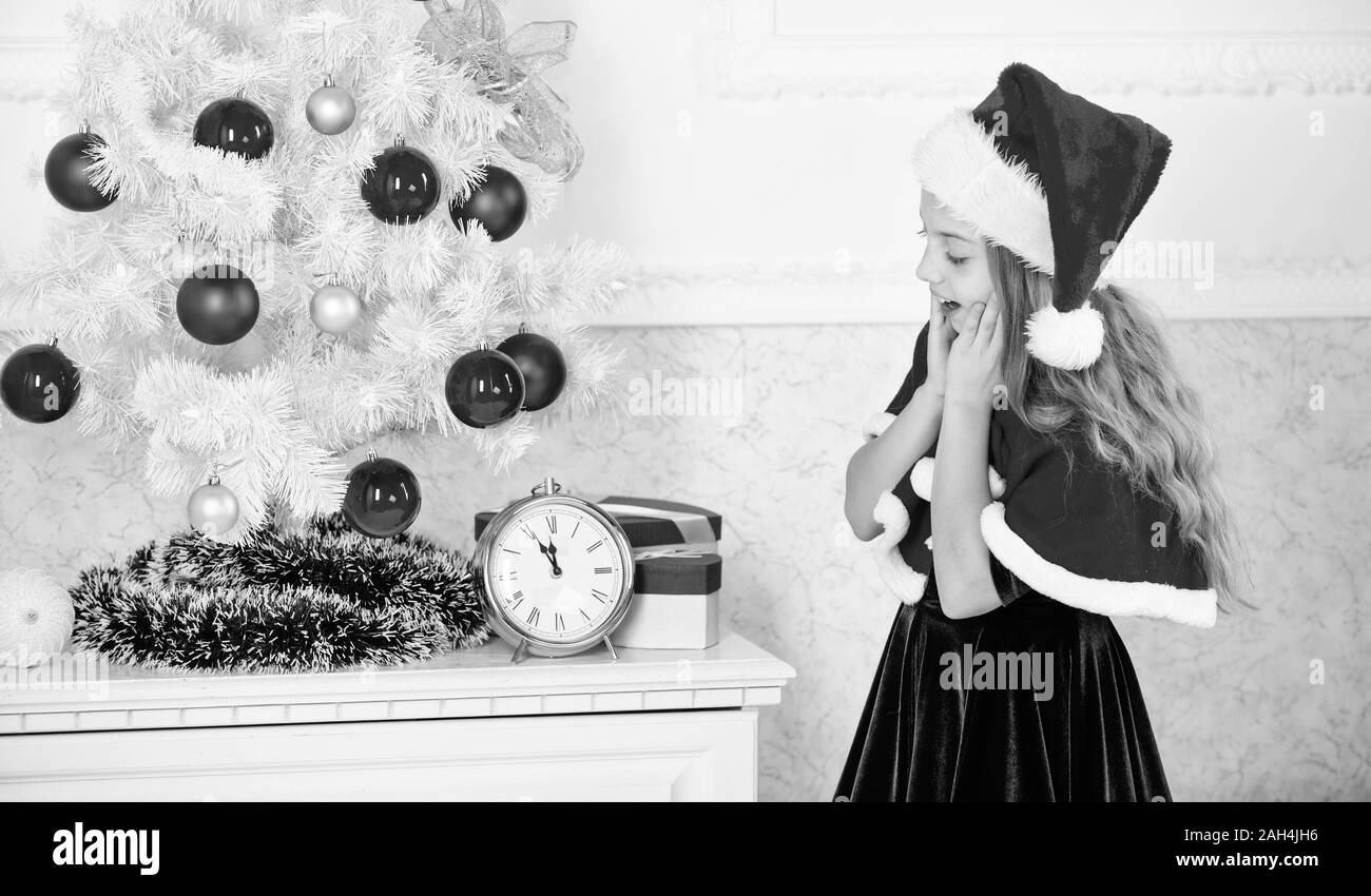 New year countdown. Last minute new years eve plans that are actually lot of fun. Girl kid santa hat costume with clock counting time to new year. How much time before. Last minute till midnight. Stock Photo