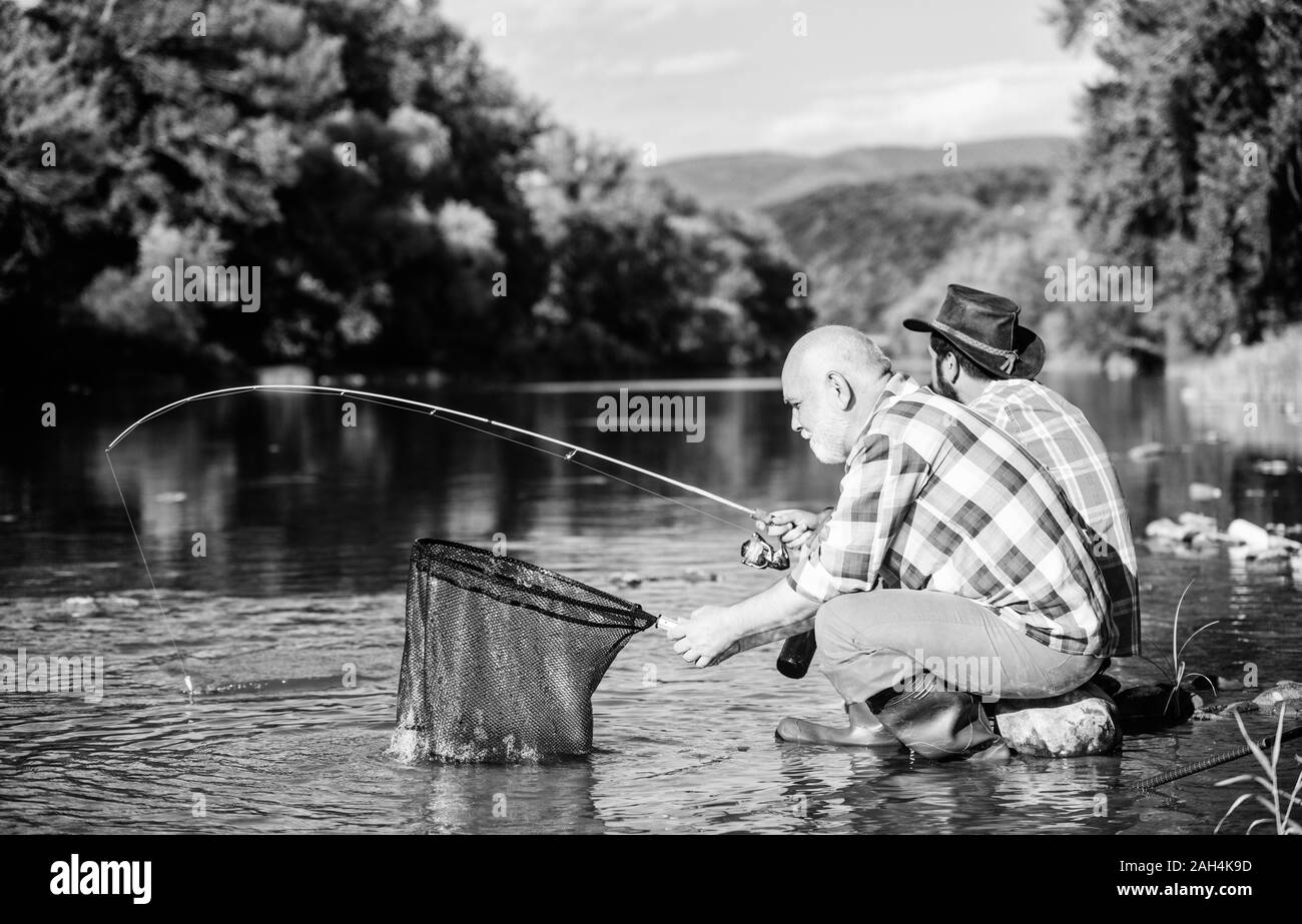 Beautiful evening riverside. Men riverside catching fish. Teaching fishing.  Sharing his secrets. Transferring knowledge. Friends spend nice time at  riverside. Experienced fisherman show tips to son Stock Photo by ©stetsik  332936230