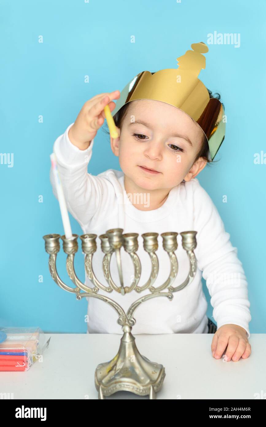 Kid celebrating Hanukkah Israel holiday. Little jewish boy puts candles ...