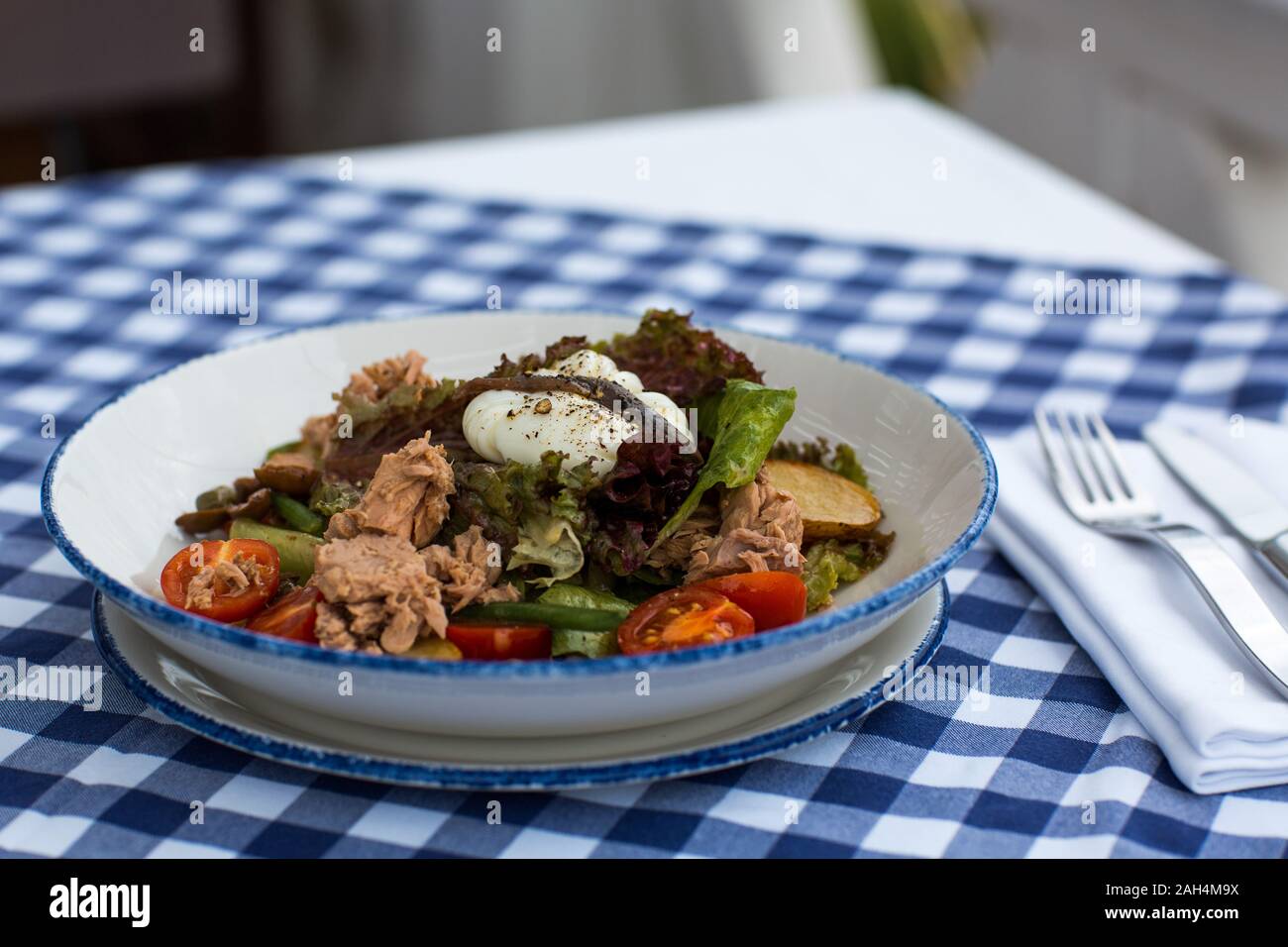 Nicoise salad in a plate on the table daylight Stock Photo