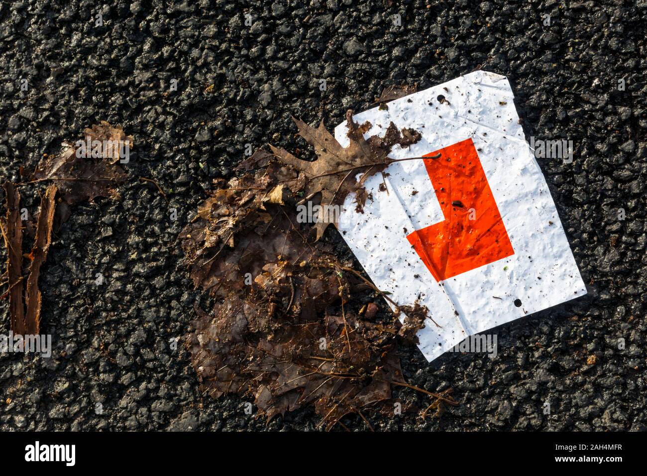 Screwed up L plate abandoned on a tarmac road. Stock Photo