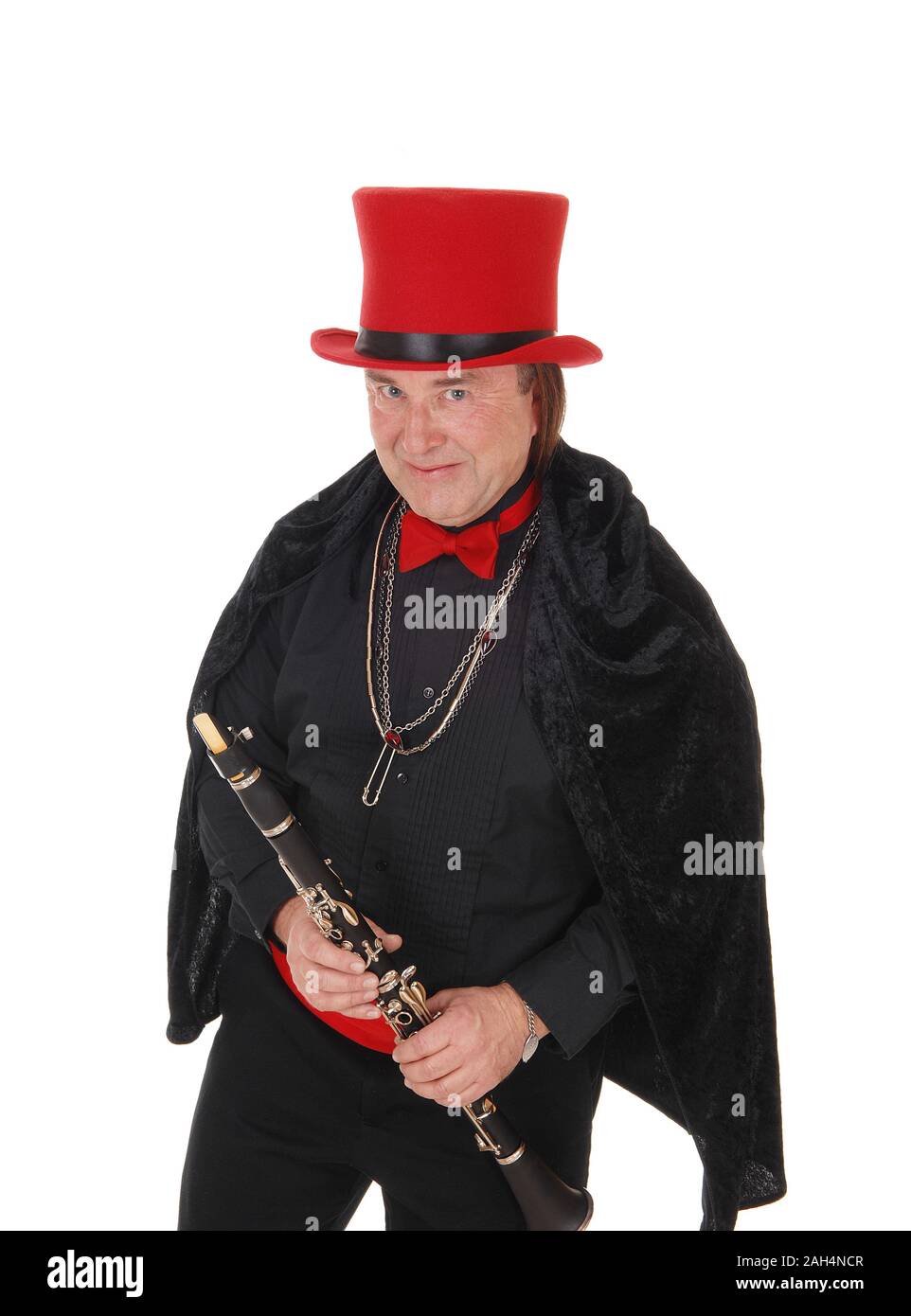 A middle age indigenous man holding his clarinet in a black outfit and red hat and bow tie looking at camera, isolated for white background Stock Photo
