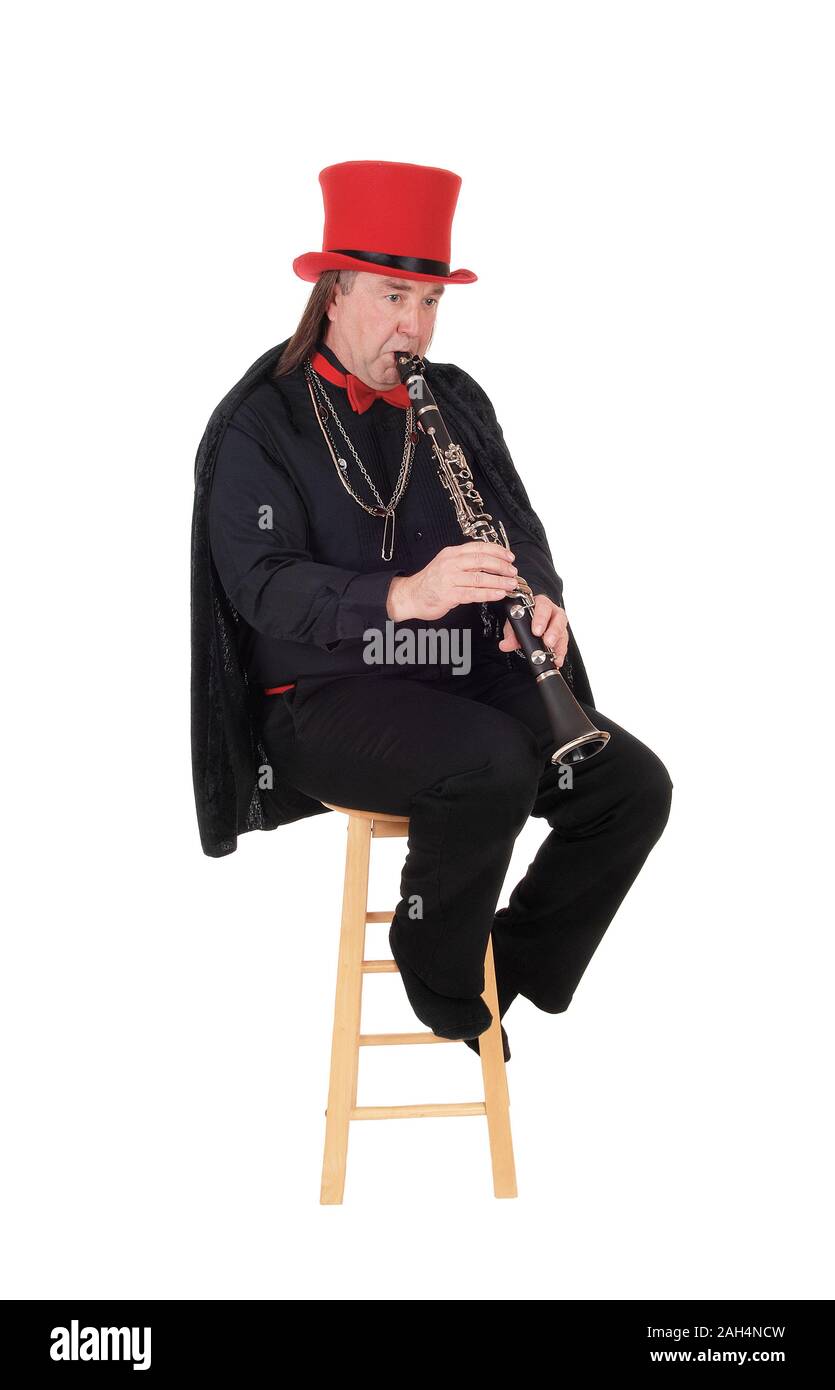 A middle age indigenous man playing his clarinet in a black outfit and red hat and bow, isolated for white background Stock Photo