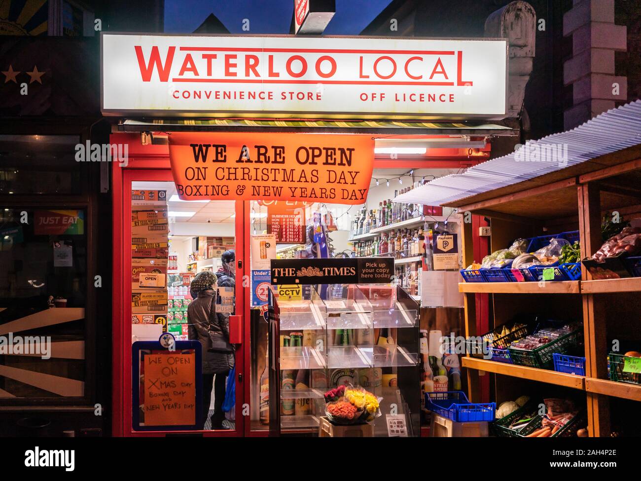 Local convenience store at night with a sign 'we are open on Christmas Day' displayed outside in Southampton, England, UK Stock Photo