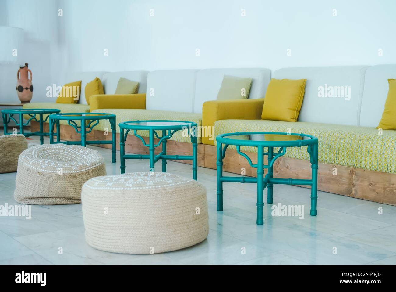 Light hall room with natural fabric puffs, green tables, and sofa with ...