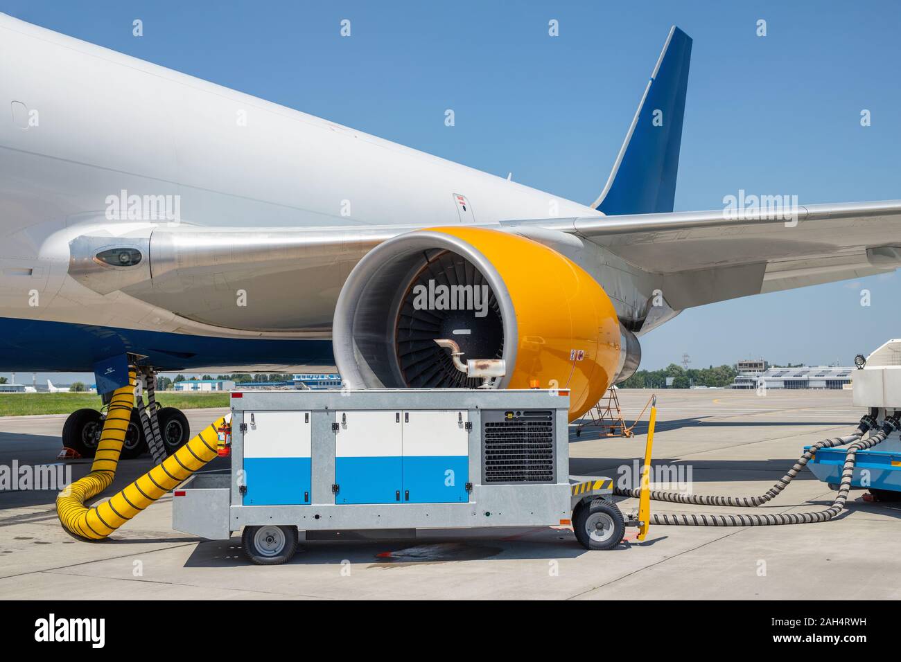 Big modern commercial cargo freight plane parked on airport runway and connected to ground supply power unit. Aircraft maintenance service and check Stock Photo