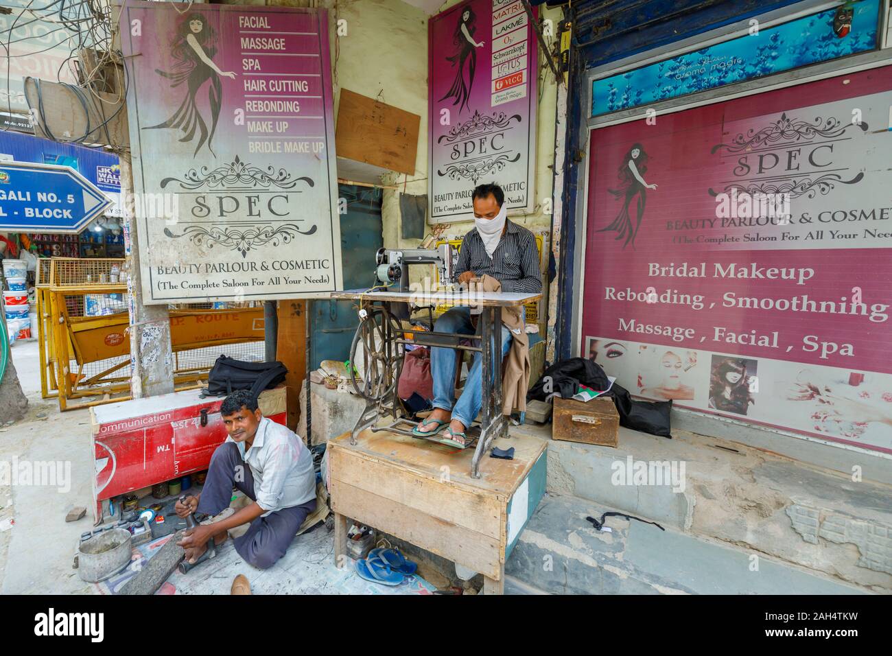 Street scene, Mahipalpur district, a suburb near Delhi Airport in New Delhi, capital of India: local man working with an old-fashioned sewing machine Stock Photo