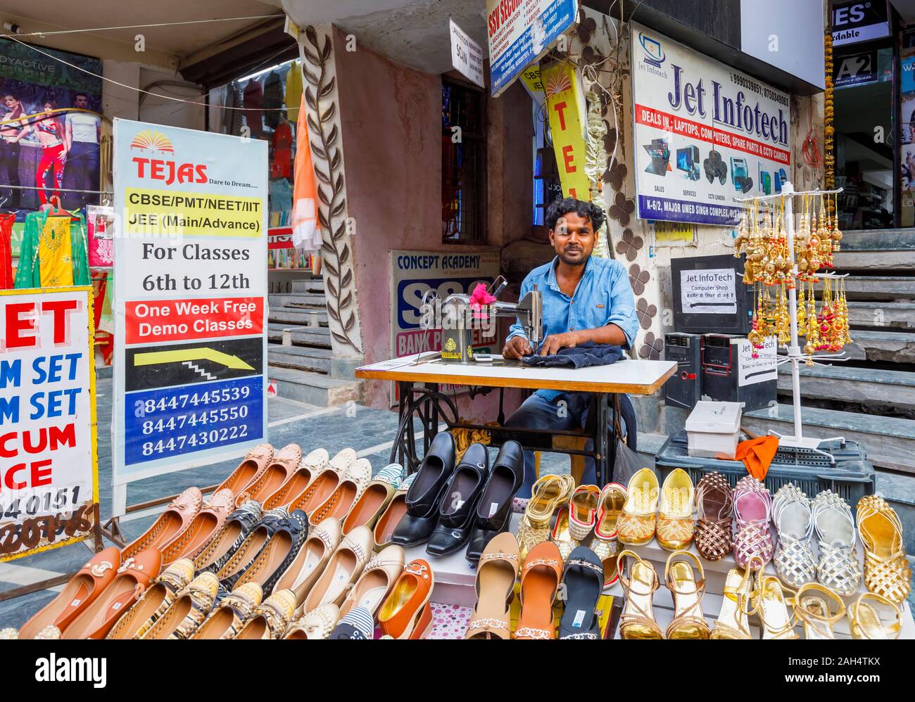 Street scene in Mahipalpur district, a suburb near Delhi Airport in New Delhi, capital city of India: local man working with a manual sewing machine Stock Photo