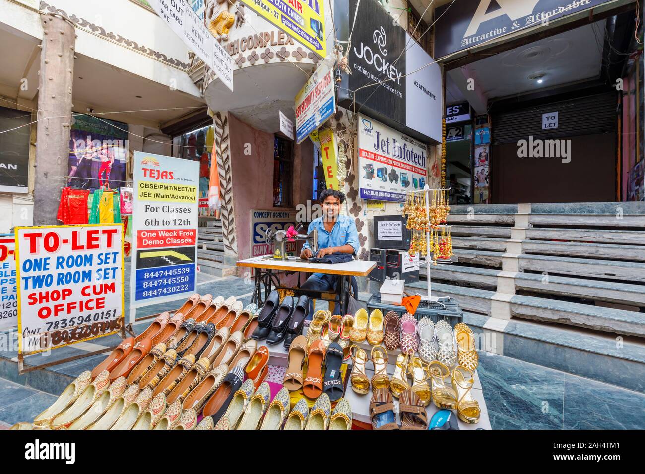 Street scene in Mahipalpur district, a suburb near Delhi Airport in New Delhi, capital city of India: local man working with a manual sewing machine Stock Photo