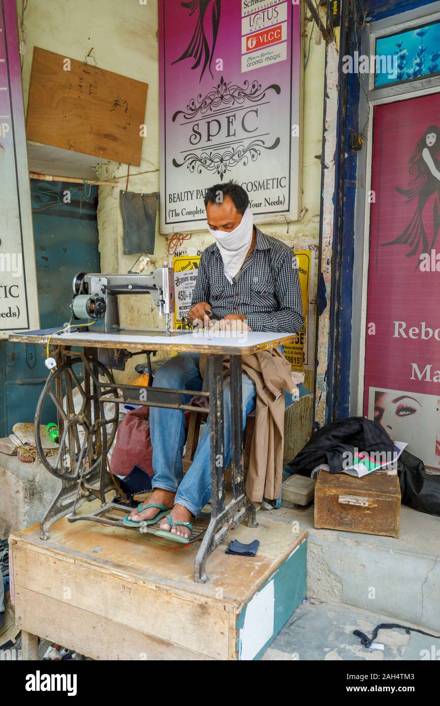 Street scene, Mahipalpur district, a suburb near Delhi Airport in New Delhi, capital of India: local man working with an old-fashioned sewing machine Stock Photo