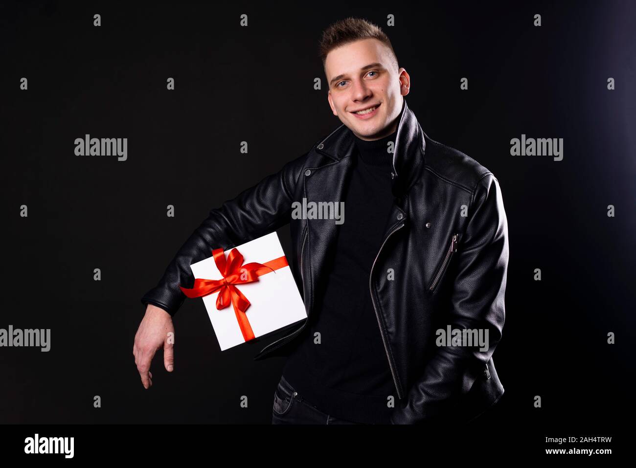 Men holding gift box for 14 February, holiday and christmas concept. Isolated over black background. Stock Photo
