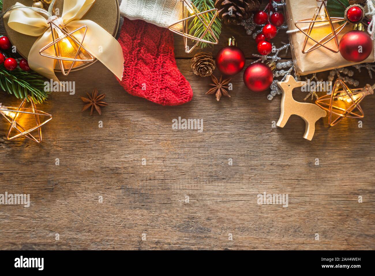 Holiday Christmas card background with festive decoration ball, stars, snowflakes, gift box, pine cones on a wood background from Flat lay, top view. Stock Photo