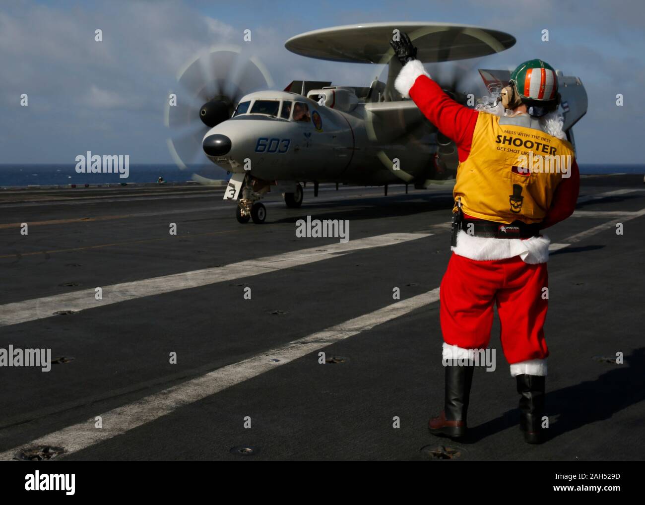 USS Abraham Lincoln, United States. 24 December, 2019. A U.S. Navy sailor dressed as Santa Claus directs an E-2D Hawkeye aircraft on the flight deck of the Nimitz-class aircraft carrier USS Abraham Lincoln during operations on Christmas Eve December 24, 2019 in the South China Sea.  Credit: Amber Smalley/U.S. Navy/Alamy Live News Stock Photo
