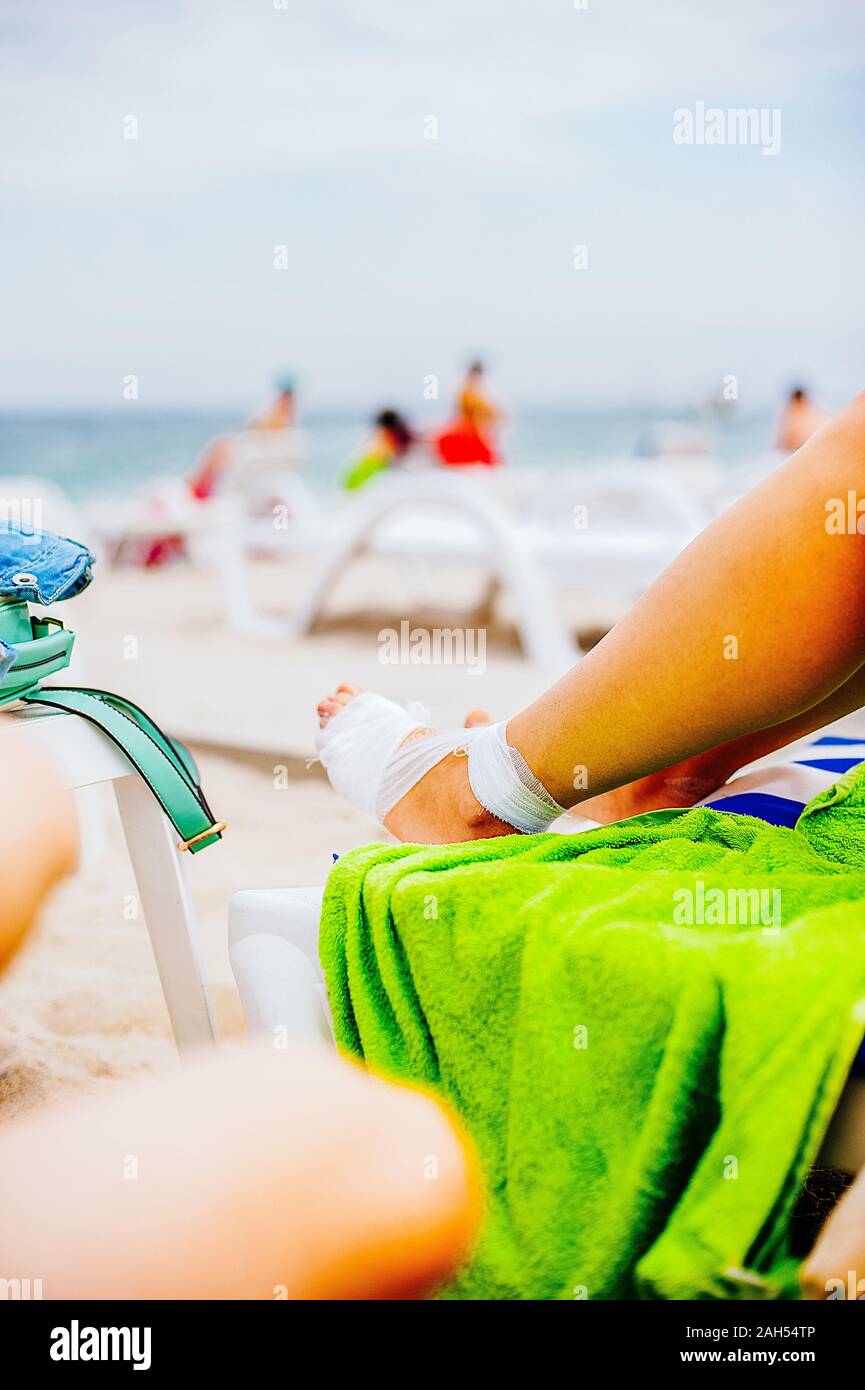 Gauze bandage the treating patients with man is wrapping his foot injury on the beach Stock Photo