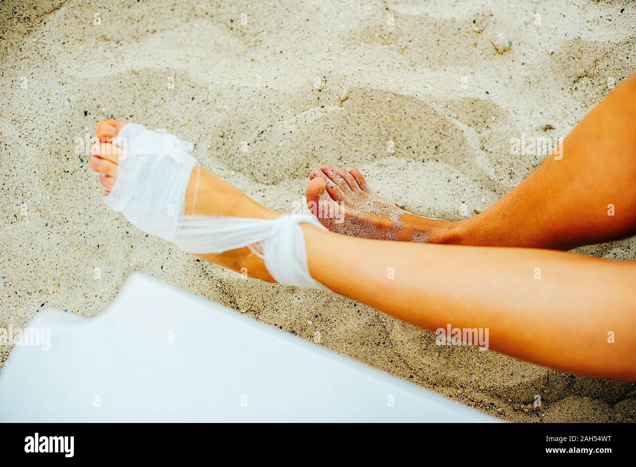 Gauze bandage the treating patients with man is wrapping his foot injury on the beach Stock Photo