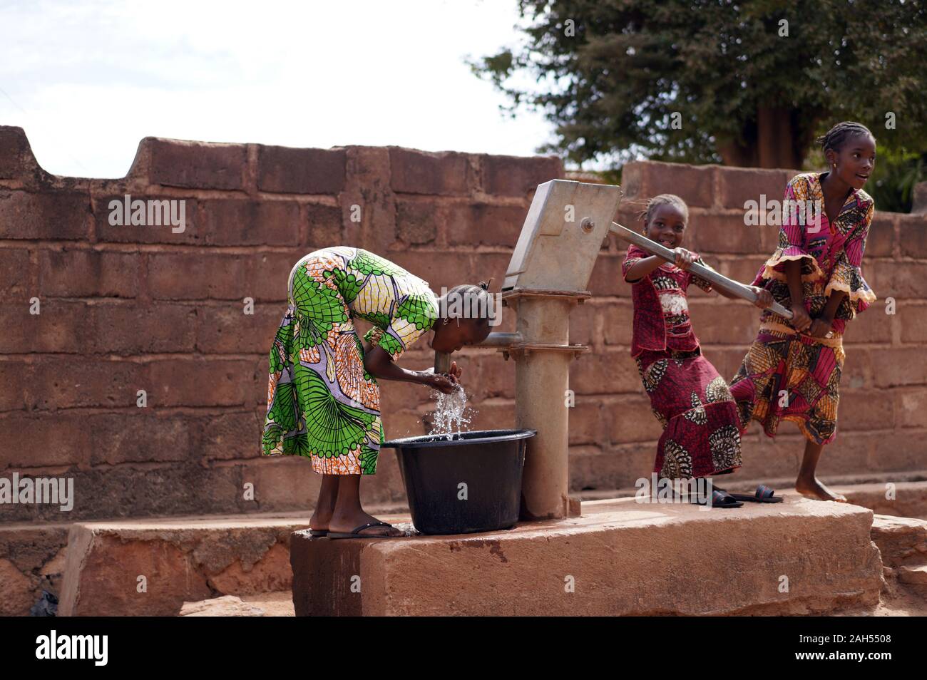 Three Little African Girls Proud Of Successfully Pumping Water Out of a Village Borehole Stock Photo