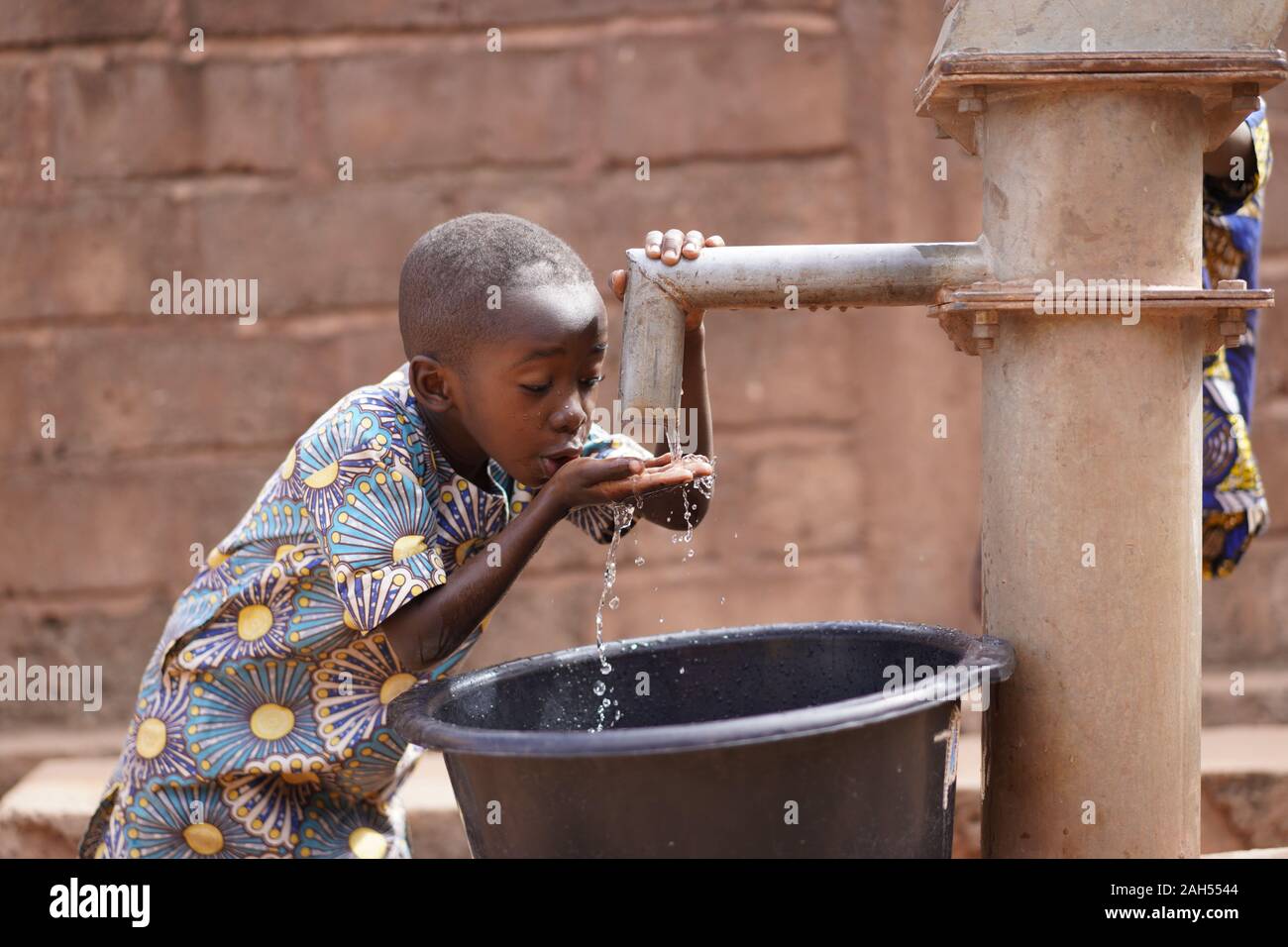 Small African Boy Sipping Clean Fresh Water From A Modern Pumping Station Stock Photo